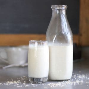 glass of white milk beside half-filled milk bottle