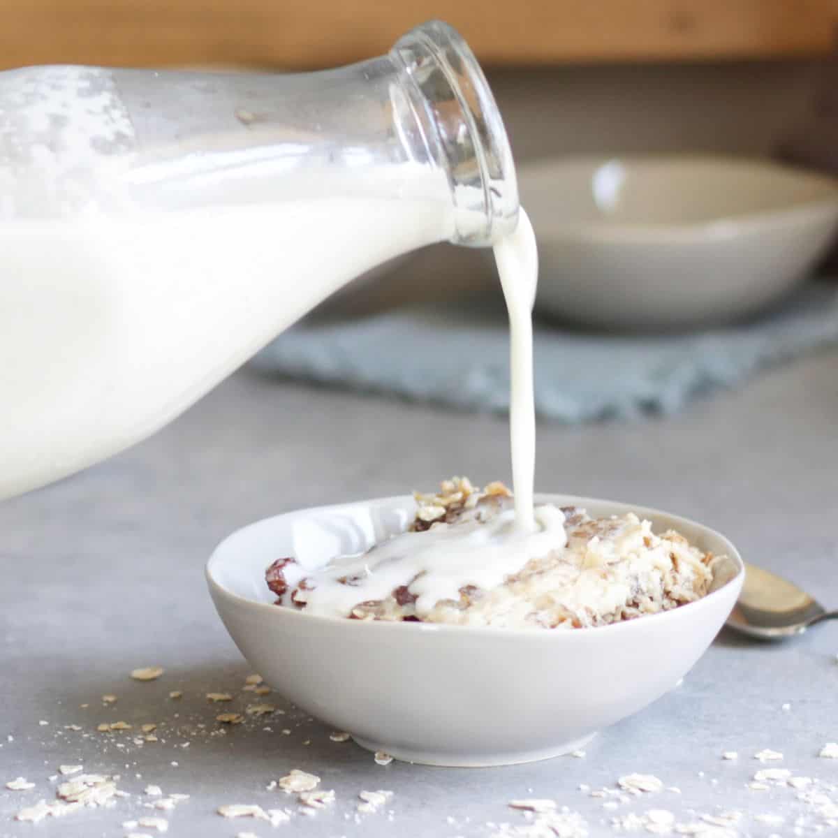 milk pouring from a bottle over cereal in a bowl