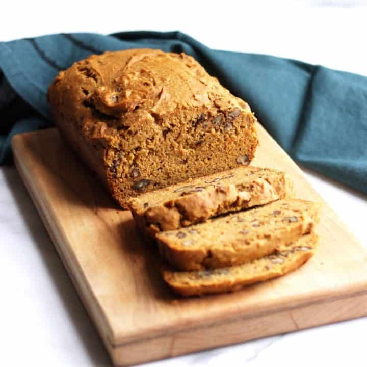 sweet potato bread partially sliced on wooden board with teal napkin in background