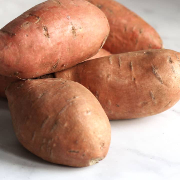 pile of unpeeled, raw sweet potatoes