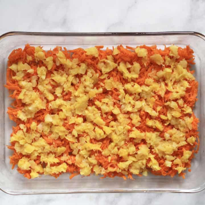 layer of shredded carrots over bottom of glass pan with a layer of crushed pineapple overtop