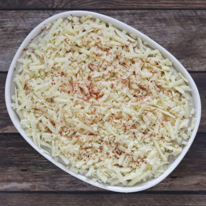 paprika sprinkled over white cheese in white baking dish