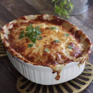 white dish of scalloped potatoes with browned cheesy topping, garnished with parsley