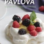 raspberries and blackberries rest on a cloud of whipped cream and meringue base with text, "Pavlova"