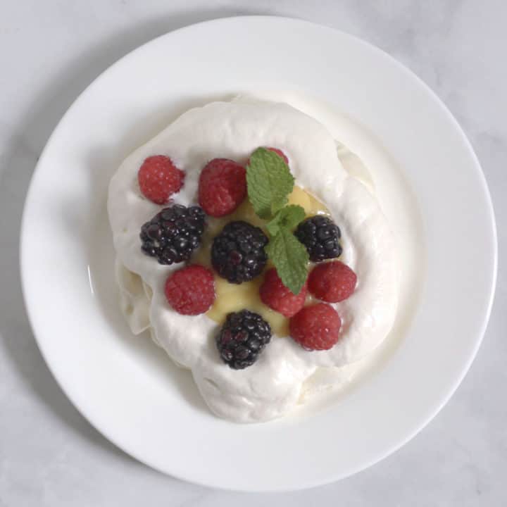 fresh berries and mint leaves on a cloud of whipped cream, seen from above