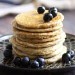 stack of golden pancakes, topped with syrup and blueberries.
