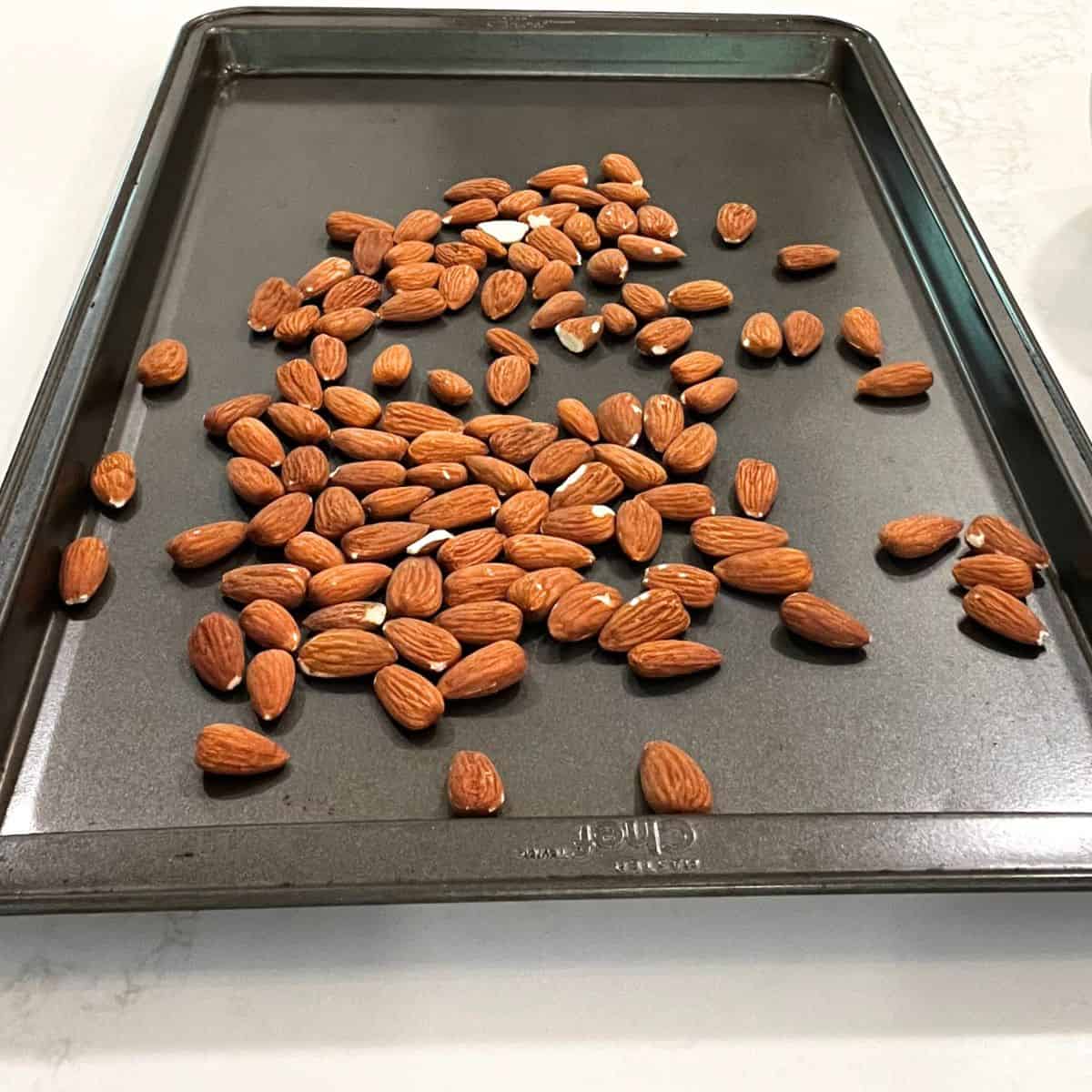 whole almonds spread out on a baking sheet.