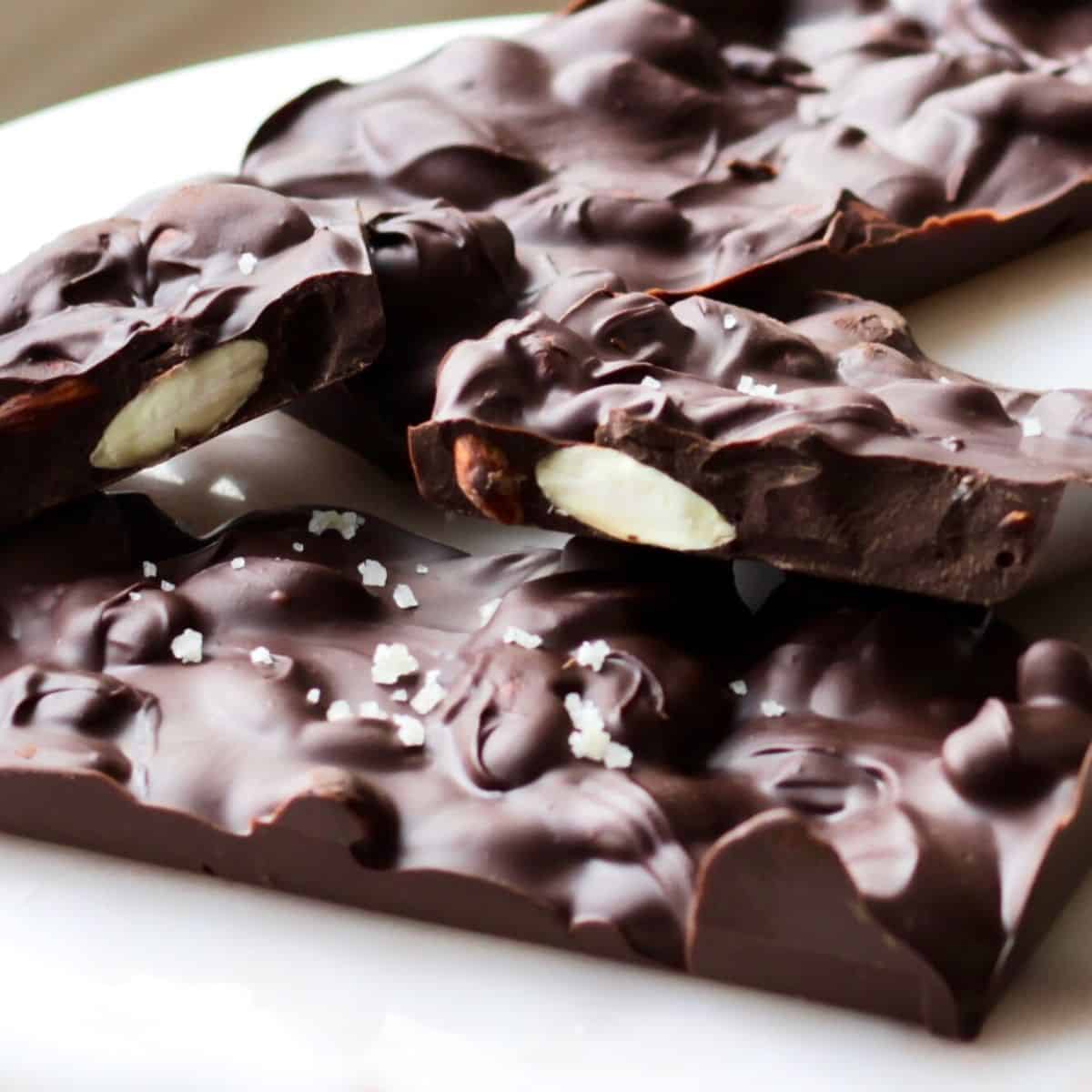 closeup of pieces of chocolate bar with pieces of almond and salt sprinkled on topk
