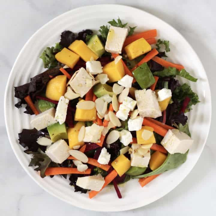 chicken mango avocado salad with cubed chicken and feta and sliced almonds on top