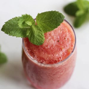 looking down on a glass of deep pink slush garnished with mint leaf