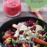 chicken waldorf salad in black bowl with clear pitcher of raspberry vinaigrette in background