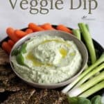 looking down on a shallow bowl of avocado dip surrounded by seed crackers and veggies