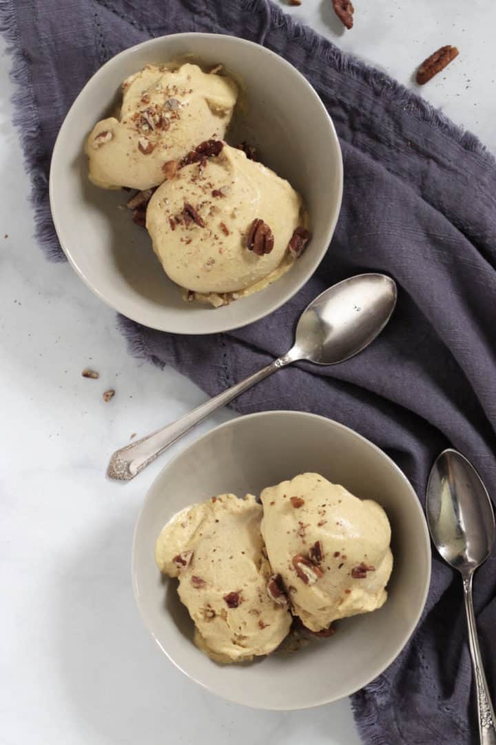 looking down on two bowls of cream ice cream with nuts sprinkled on top