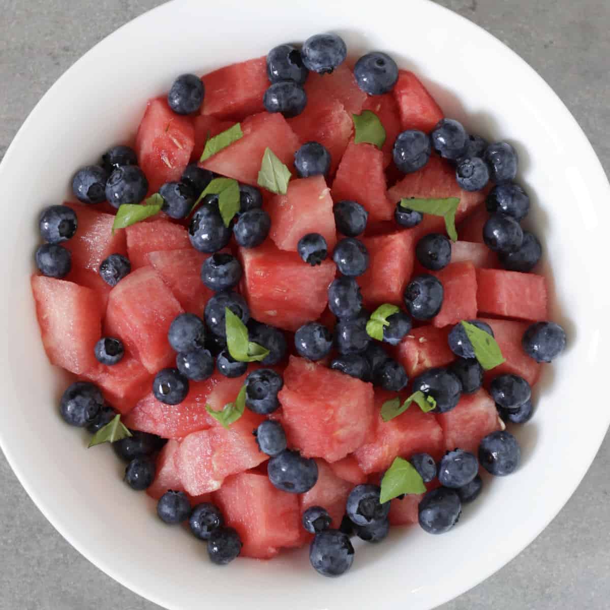 chopped basil sprinkled over watermelon chunks and blueberries