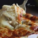 closeup of forkful of creamy scalloped potatoes being lifted from surface of melted cheese