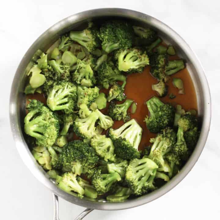 broccoli in pan with added coconut aminos and honey showing on bottom