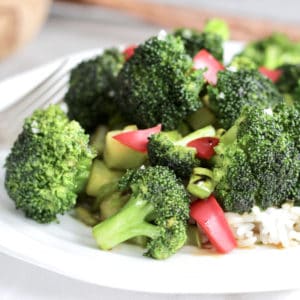 closeup of broccoli stir fry on white plate, viewed from an angle