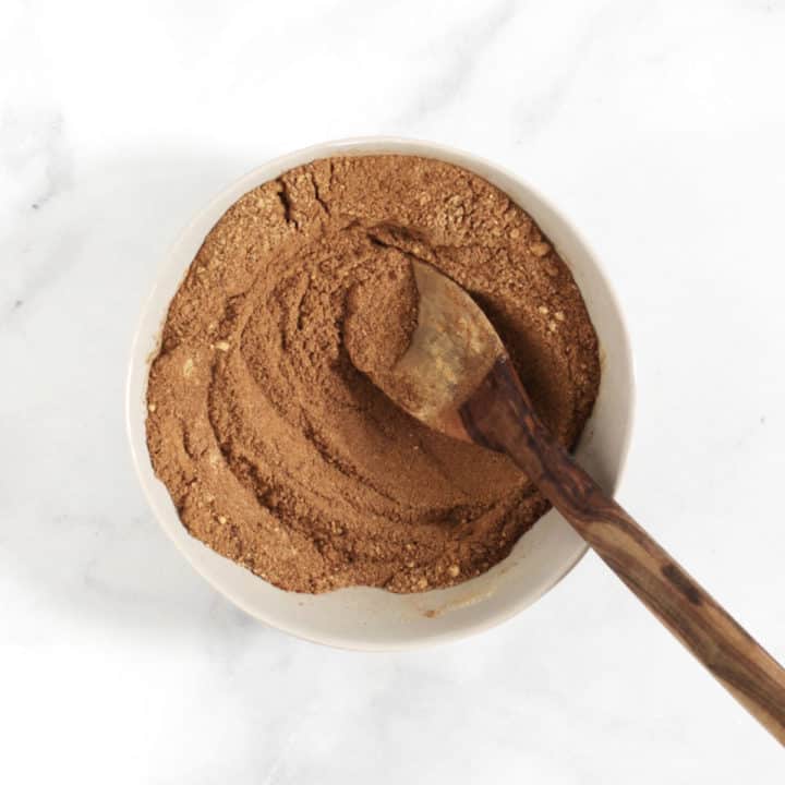 looking down into a shallow dish with brown spices stirred together with a wooden spoon