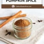 pumpkin spice in jar on linen napkin with cinnamon sticks.