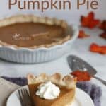single piece of pumpkin pie served on a white plate with whipped cream topping, remainder of whole pie in background