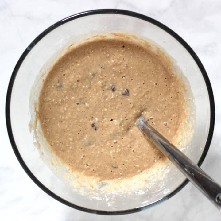 spoon handle sticking out of batter in glass bowl on white surface