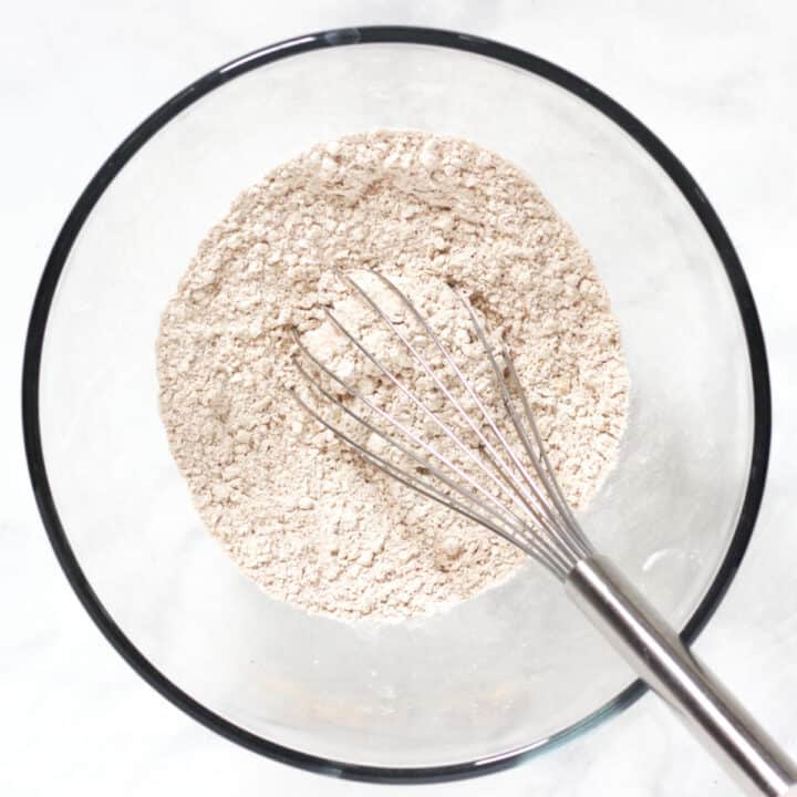 whisk sitting in dry flour mixture in glass bowl