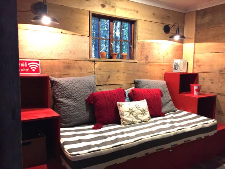 day bed between red shelves in front of wood walls with lights shining down