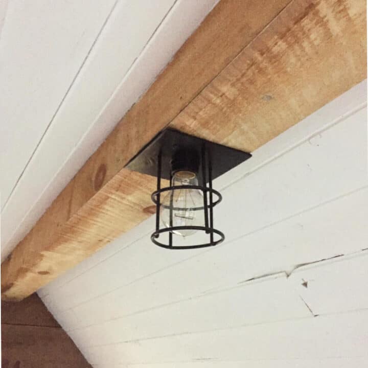 Edison light bulb in frame of black rings on natural wood beam