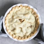 looking straight down on a pie topped with a nicely baked golden crust, all in a white pie pan