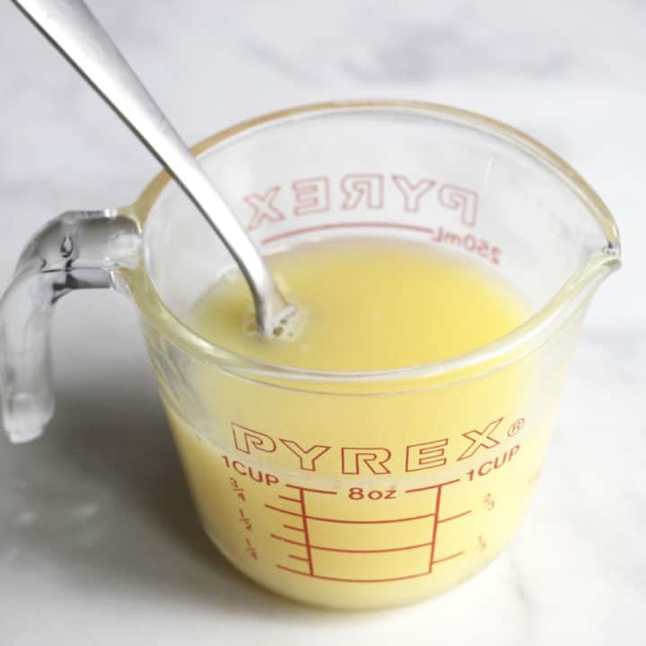 fork stirring pale yellow liquid in measuring cup