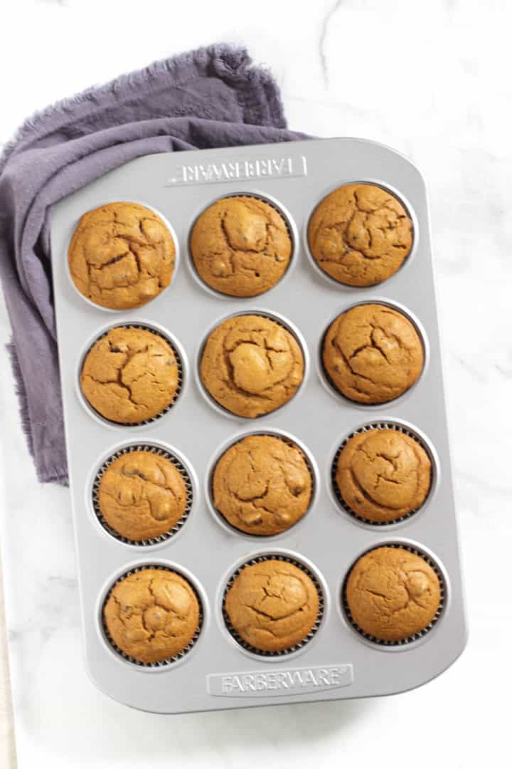 looking down on pan of golden, baked muffins with lavender napkin