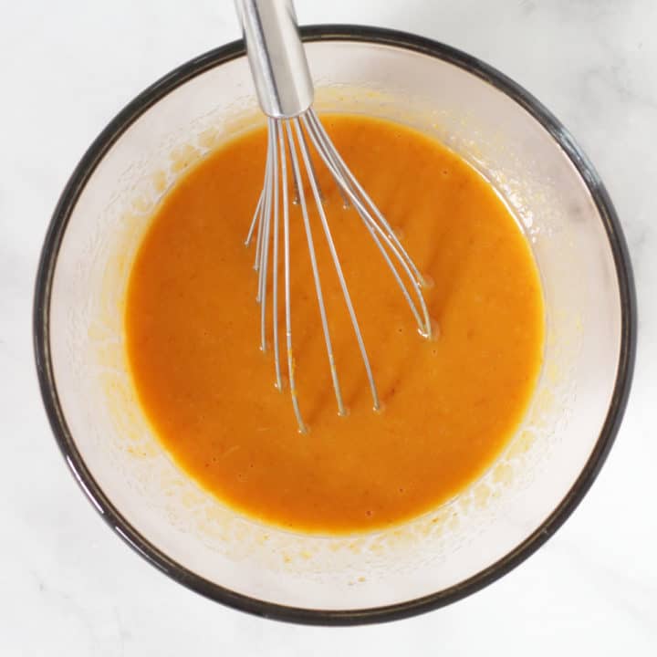 orange pumpkin liquid and whisk in glass bowl on marble