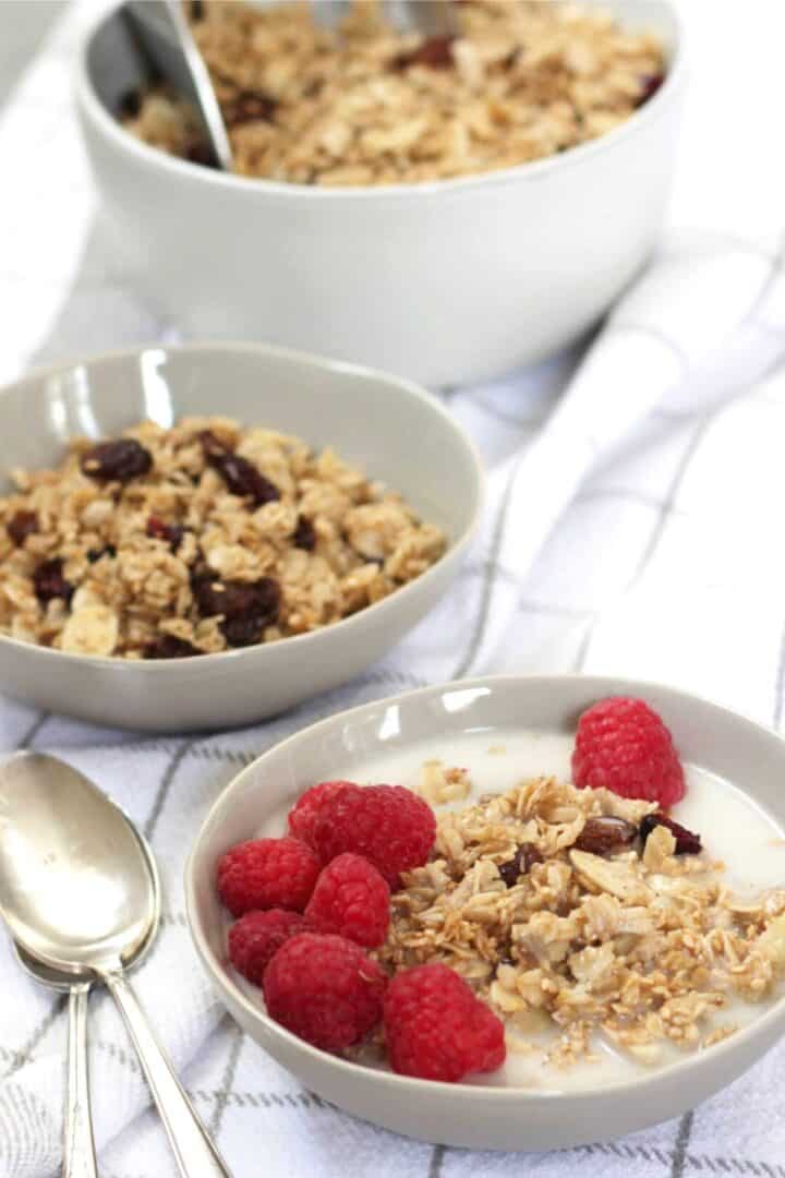 three bowls of homemade granola with berries on the front one