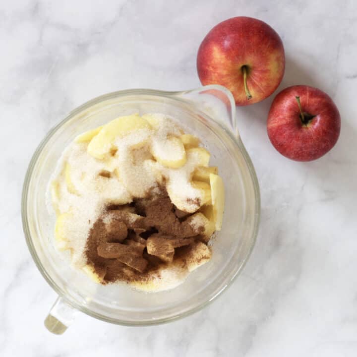 cinnamon, sugar, and sliced apples in glass bowl