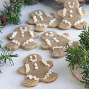 random gingerbread men scattered on white surface with bits of greenery