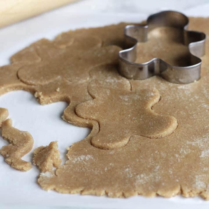 gingerbread men being cut out of dough with cookie cutter