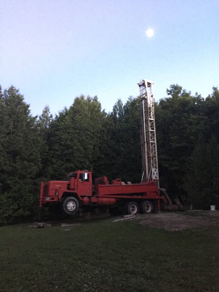 red  truck with tall well driller behind it