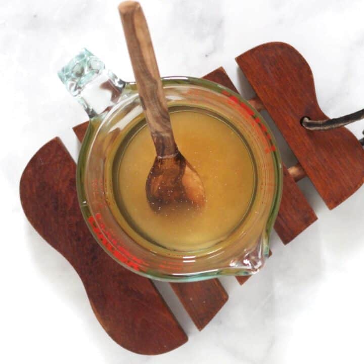 wooden spoon resting in golden liquid in pyrex measuring cup