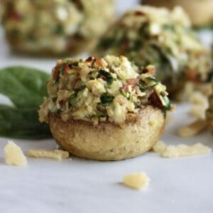 closeup of stuffed mushroom with toasted cheese and spinach topping spilling out