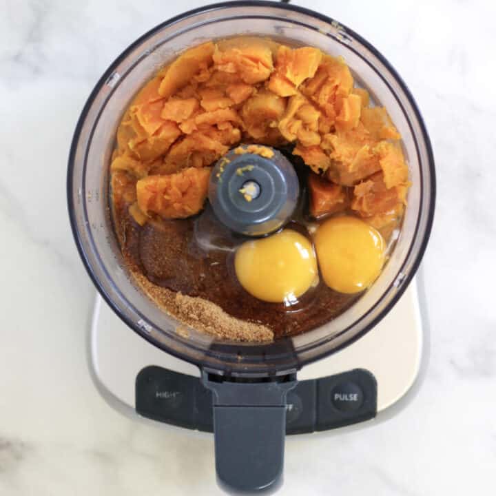 chunky, cooked sweet potatoes, sugar, and eggs in bowl of food processor