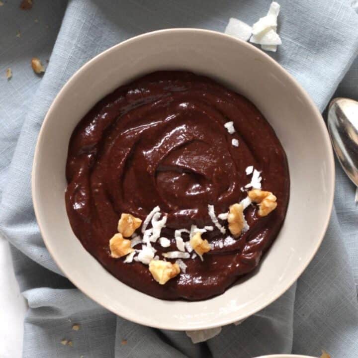 bowl of chocolate pudding with sprinkles of coconut flakes and chopped nuts on top