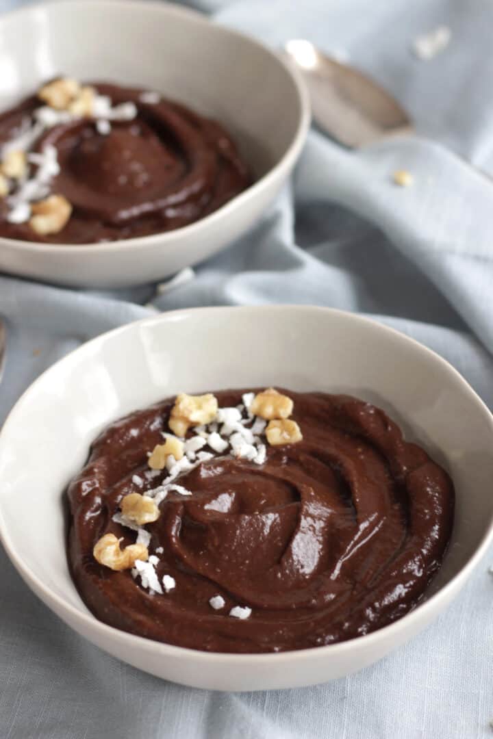 two bowls of chocolate garnished with flaked coconut and chopped nuts