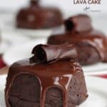 individual little round chocolate lava cakes garnished with ganache and a chocolate curl
