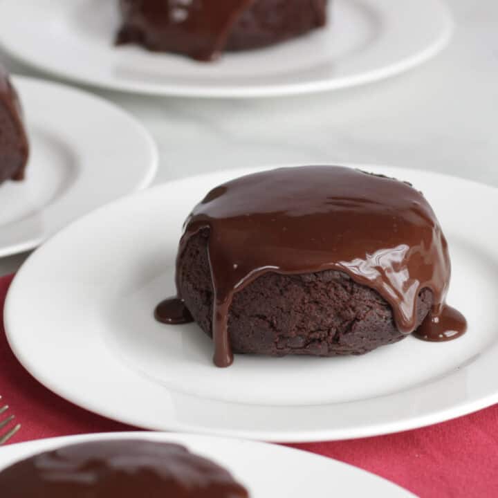 dark brown chocolate ganache dripping over the top and down the sides of a small, round chocolate cake