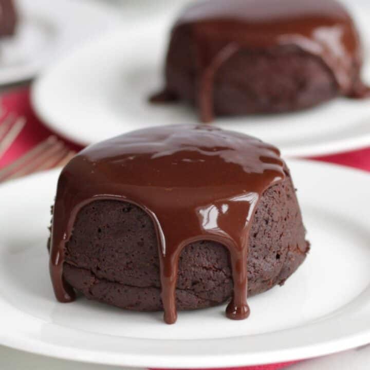 liquid dark chocolate flowing over top and down sides of a small round cake