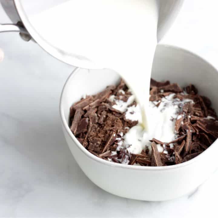 steaming milk is poured over a bowl of finely chopped chocolate