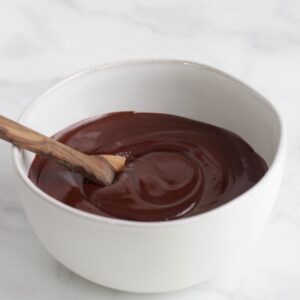 spoon in smooth, liquid dark chocolate in white bowl