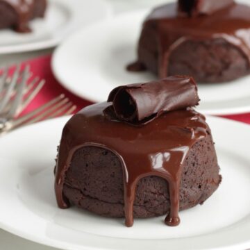round chocolate cake with ganache dripping down the sides and a chocolate curl on top