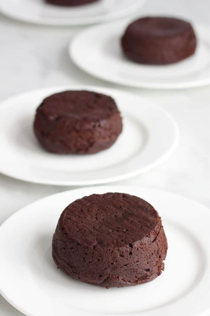 small round, cooked, chocolate cakes sitting on individual white plates