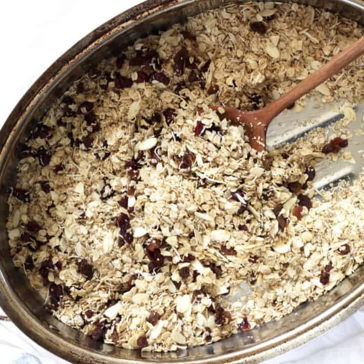 granola with dried raisins and cranberries scattered throughout in a large roasting pan